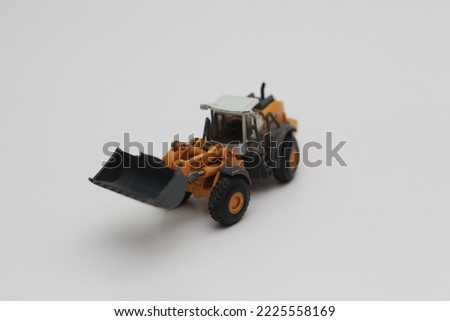 a close up of miniature orange wheel loader toy isolated on white background. concept photo of heavy equipment miniature toy.