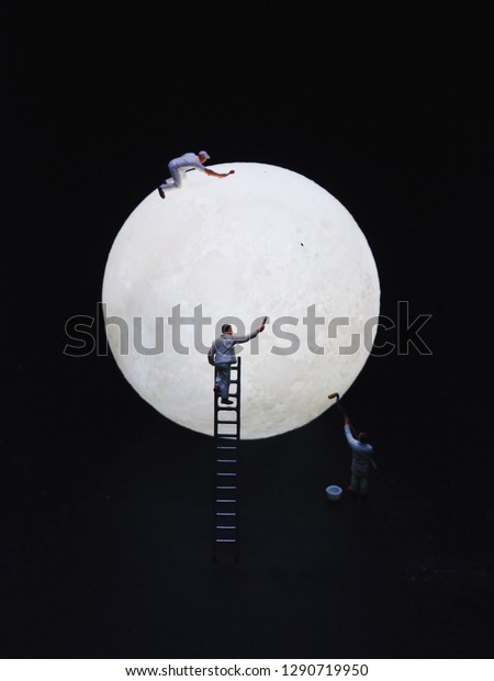 Close up miniature people painting color on the\
full moon.