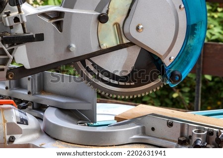Close up of miter saw in the process of sawing off a wooden part.