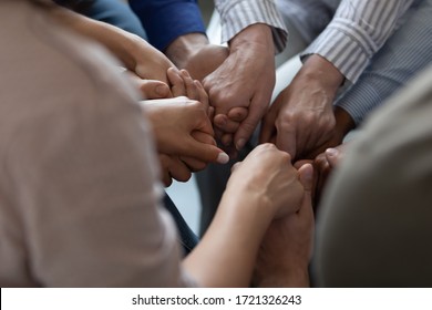 Close up mixed race business people holding hands together, support and unity concept. Diverse colleagues joining in team building activity, staff training concept, teamwork relationship. - Shutterstock ID 1721326243