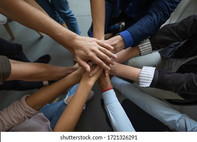 Close up mixed race business people putting hands together, support and unity concept. Diverse colleagues joining in team building activity, staff training concept, start working together, teamwork.