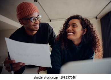 Close up of mixed race couple using laptop for online banking. Happy African American couple smiling and looking at each other while working together at home. High quality photo