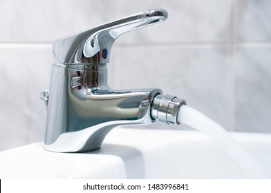 Close up of the mixer tap of a bidet with running water. The bidet was invented in France in the 1700s