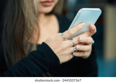 Close up of mobile phone using partial blurred young woman