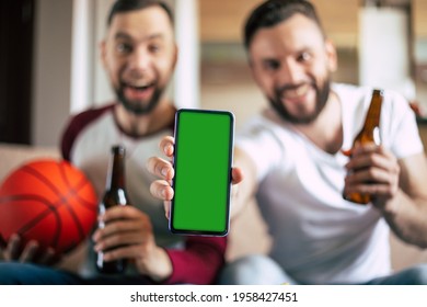 Close up mockup photo of green blank screen on the smart phone in hand of excited young bearded sports fans. Winning in bets - Powered by Shutterstock