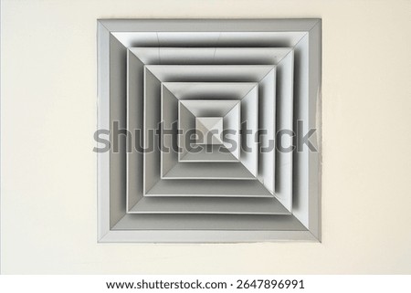 Close up of a modern air vent diffuser on a ceiling, featuring clean geometric design with layered square shapes, industrial concept for HVAC, ventilation systems, and architecture backgrounds