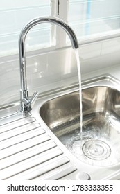 Close Up Of Modern Kitchen Metal Faucet And Metal Kitchen Sink With A Running Water.