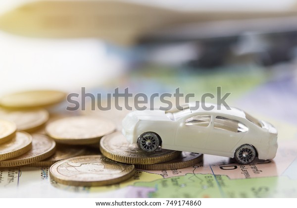 Close up modern of model white toy\
car park on stack golden coins. Saving, Financial and Installment\
payment concept. and blurred airplane\
background.