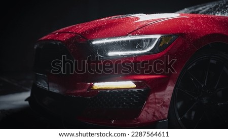 Close Up of a Modern Red Performance Car in a Dark Studio Environment. Creative Led Headlights Photo of a Performance Sportscar Dripping in Water After a Detailed Car Wash
