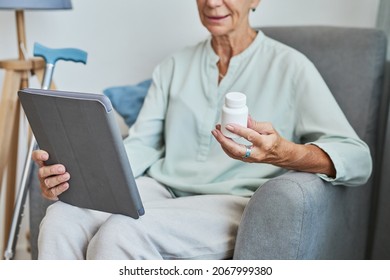 Close Up Of Modern Senior Woman Holding Prescription Bottle At Home And Using Digital Tablet, Copy Space