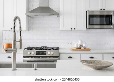 Close Up Modern White Kitchen with Stainless Steel Luxury Appliances. Contemporary dual tone cabinets with white subway tile backsplash.