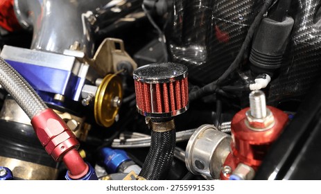 Close up of a modified high-performance car engine bay featuring a custom breather filter and anodized fittings