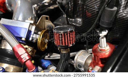 Close up of a modified high-performance car engine bay featuring a custom breather filter and anodized fittings