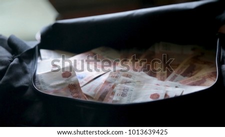Close up money cash in black bag. Stacks of money in black bag. Case full of money on gray background