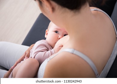close up of mother breast feeding her newborn baby girl at home