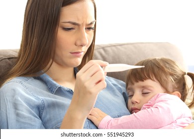 Close up of a mother checking the temperature of her ill baby with a thermometer on a couch in the living room at home - Powered by Shutterstock