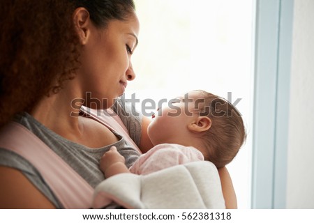 Close Up Of Mother Cuddling Baby Daughter At Home