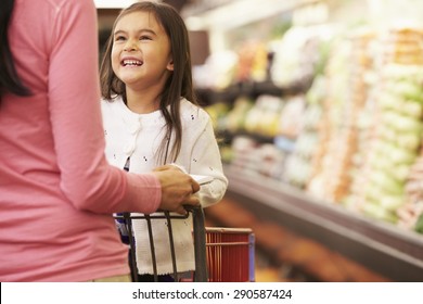 Close Up Of Mother Pushing Daughter In Supermarket Trolley