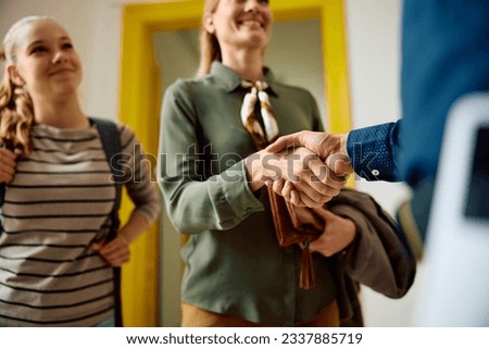 Close up of mother of a teenager girl shaking hands with high school principal.
