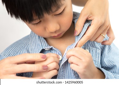 Close Up Of Mother's Hands Helping Her Adorable Kindergarten Little Asain Boy Who Misplace Button On His Shirt. 
Boy Getting Dressed, Child Development, Parenting Child, Mother's Love And Care Concept