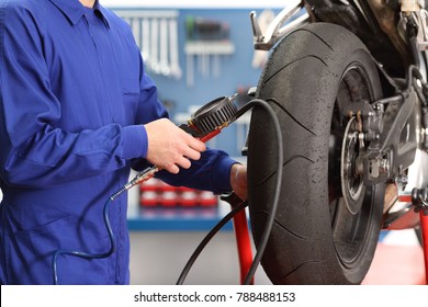 Close Up Of A Motorbike Mechanic Hand Checking Tires Air With A Pressure Gauge In A Workshop