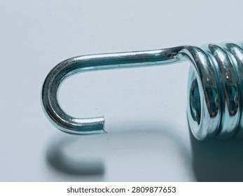 Close up of Motorcycle Kickstand Return Spring Hook Isolated on White Background , Macro close up of a shiny metal motorcycle kickstand return spring. Detail of the hook and coil. Isolated on clean white background. Automotive spare part for motorcycle repair and maintenance.
