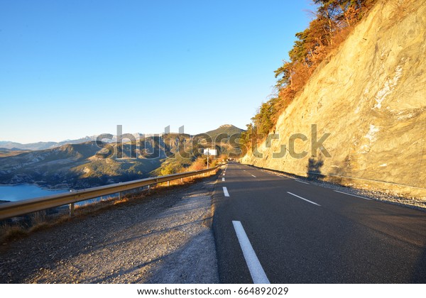 Close up of a mountain\
asphalt road in french alps near lac de Serre-Poncon. Ecrins\
massif