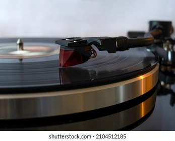 Close up of moving vinyl player from side view with red needle head. Retro and modern fusion. Vintage music player. (selective focus) - Shutterstock ID 2104512185