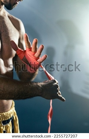 Close up of Muay Thai boxer preparing bandages for training.