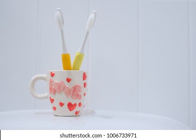 Close up mug and Couple toothbrushes in bathroom. Dental care, Love, and Valentine’s Day concept.