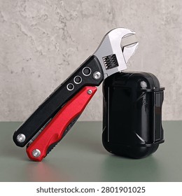 Close up of a multi tool adjustable wrench pocket knife and a black hard case on the table
