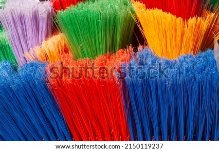 A close up of the multicoloured plastic fibres of brooms awaiting buyers