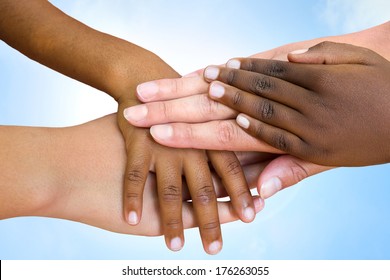 Close up of multiethnic children's hands making pile against blue sky.