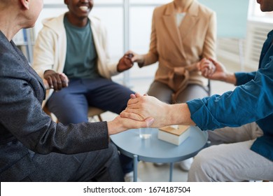 Close Up Of Multi-ethnic Group Of People Holding Hands In Prayer While Sitting In Circle In Support Group, Copy Space