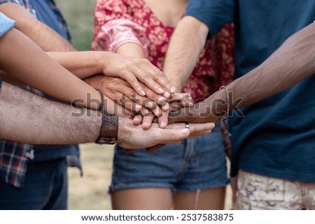 Close up of multiethnic hands joined in circle showing unity, teamwork and inclusion. Authentic moment of diverse community members symbolizing support and togetherness