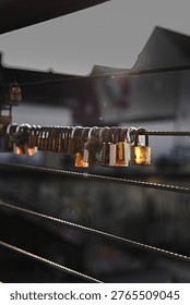 Close up of multiple love padlocks attached to a metal bridge railing, glowing in warm sunset light with soft bokeh background, symbolizing love, commitment and memories.