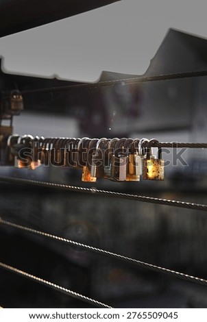 Close up of multiple love padlocks attached to a metal bridge railing, glowing in warm sunset light with soft bokeh background, symbolizing love, commitment and memories.