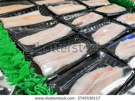 Close up of multiple packaged fish fillets arranged on artificial grass in supermarket seafood section