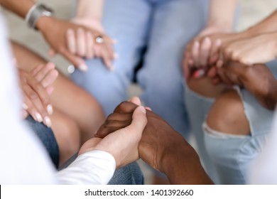 Close Up Of Multiracial People Sit In Circle Holding Hands Show Mutual Support And Understanding At Therapy Session, Diverse Men And Women Gather Give Help At Group Psychological Treatment