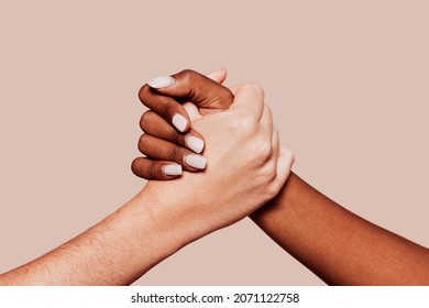 Close up multiracial woman couple with black and caucasian hands holding each other in tolerance unity love and anti racism concept. Studio shot, pastel beige background. - Shutterstock ID 2071122758