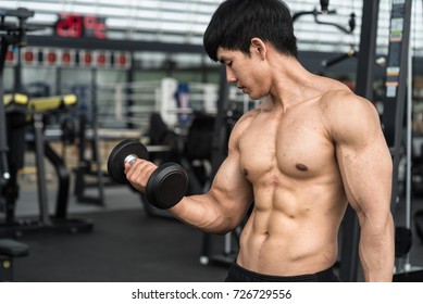 Close Up of a muscular young man lifting weights in gym
