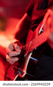 Close up of a musician playing the electric guitar during a concert, no faces are shown, shallow depth of field, vertical image