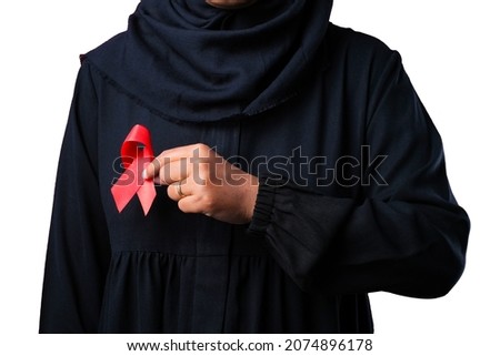 Close up of muslim asian woman in black dress holding and showing red awareness ribbon in her hands on white background