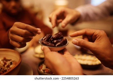 Close up of Muslim family eating dates during Iftar meal at dining table. 