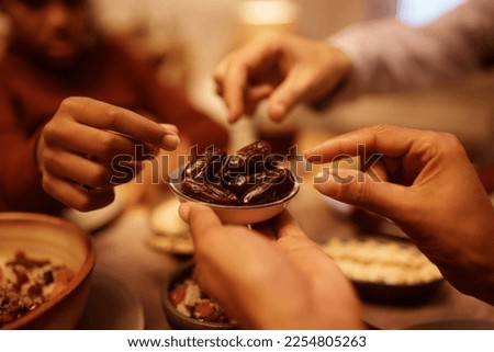 Close up of Muslim family eating dates during Iftar meal at dining table. 