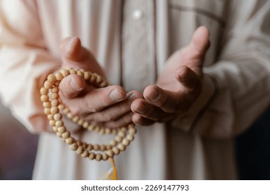 Close up of a Muslim mans hands praying and holding prayer beads. Muslim man reading holy quran - Powered by Shutterstock