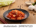 Close up Napa cabbage kimchi topped with white sesame seed in black plate,Korean fermented side dish food.