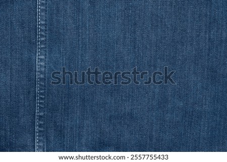Close up neat stitching pattern on blue denim jacket. Detailed fabric seam and texture of jeans material. Concept for fashion design, textile craftsmanship and clothing detail backgroundd