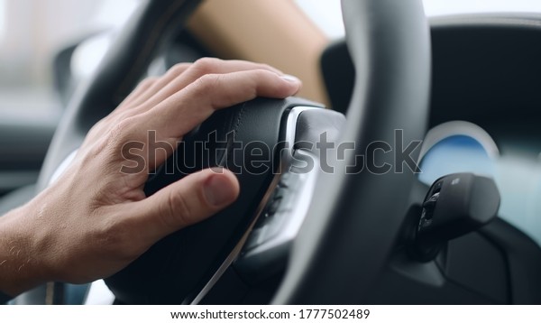 Close up nervous driver\
beeping in luxury car. Closeup male hand pushing horn on leather\
steering wheel. Stressful man hand honking in modern car in slow\
motion.