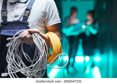 Close up of network engineer holding cables in server room during maintenance work in data center, copy space